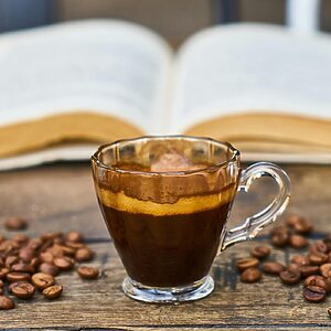 A rich espresso cup surrounded by beans and an open book, perfect for a relaxing break.